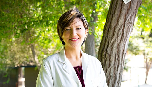 A certified addiction medical doctor smiling outdoors.